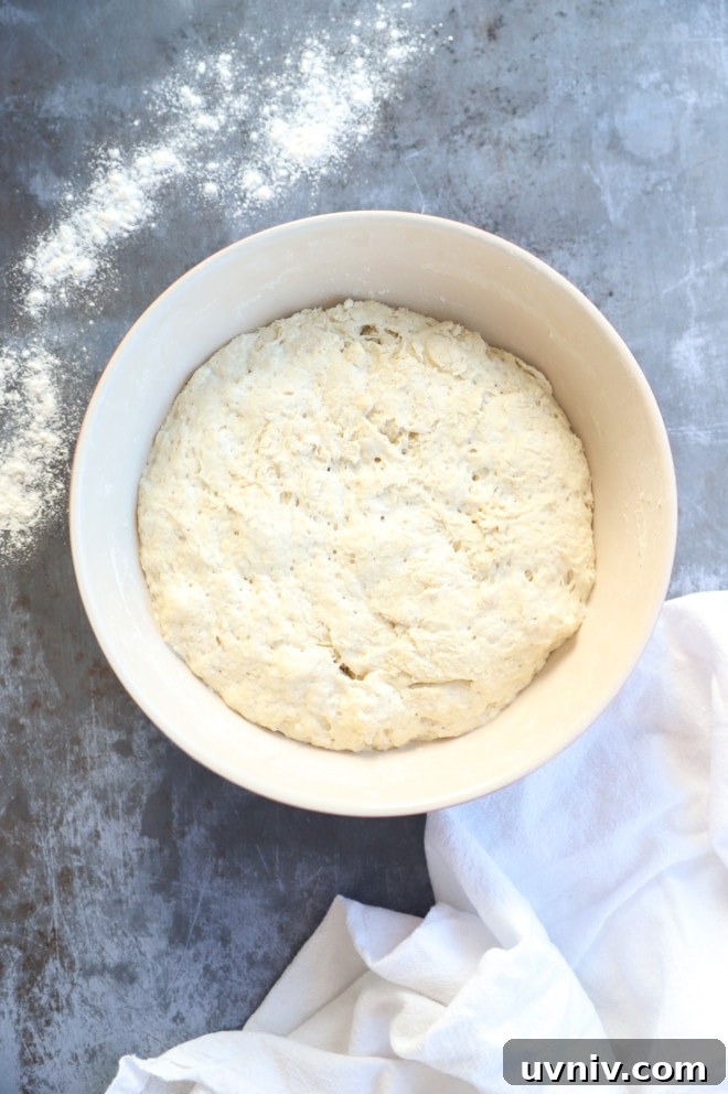 No-Knead Overnight Bread Recipe for Perfect Rustic Loaves 7 Dough rising in a bowl with flour and linen