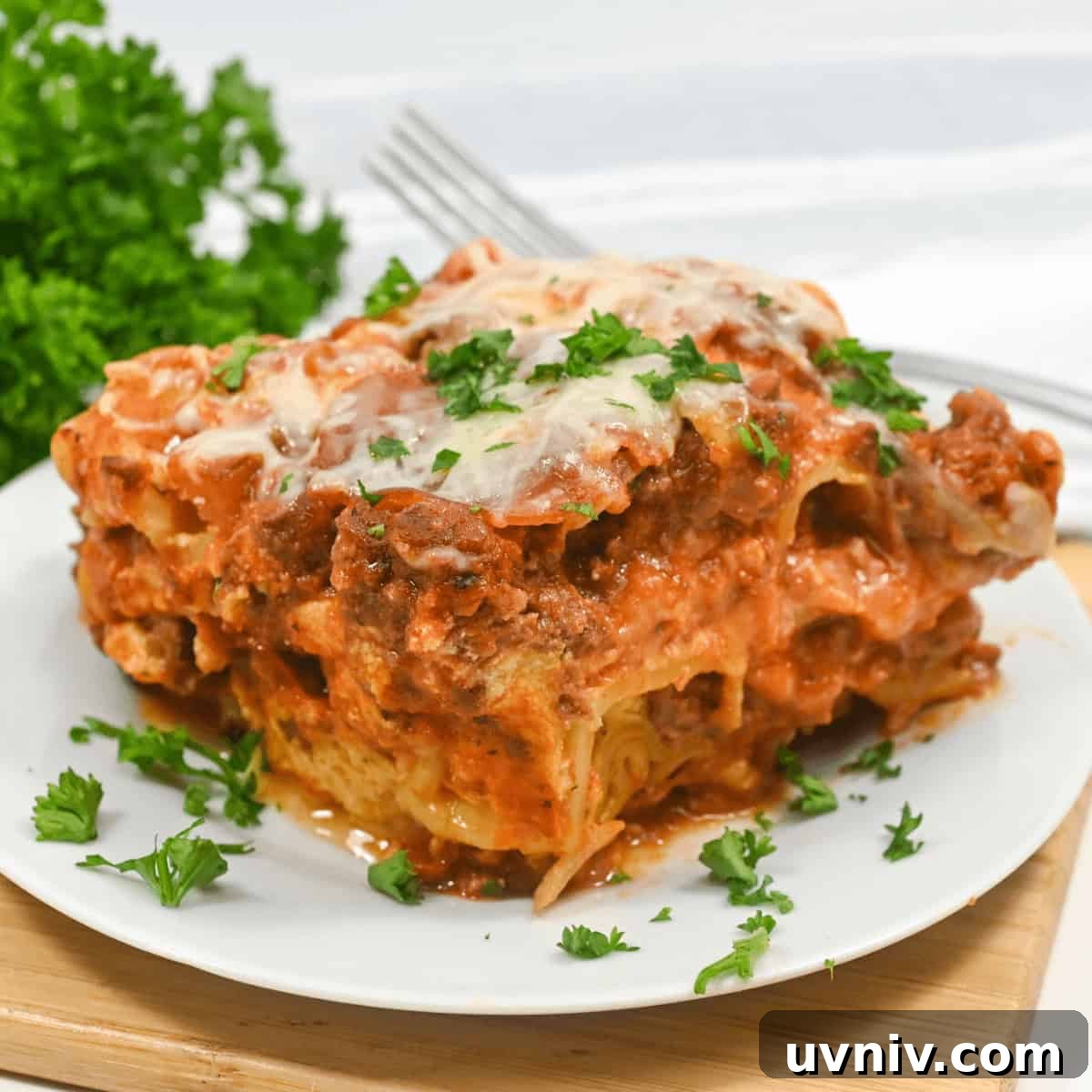 Slow Cooker No-Fuss Lasagna: Cheesy One-Pot Recipe 3 A plate with layers of pasta, meat sauce, and melted cheese, garnished with parsley on a wooden table.