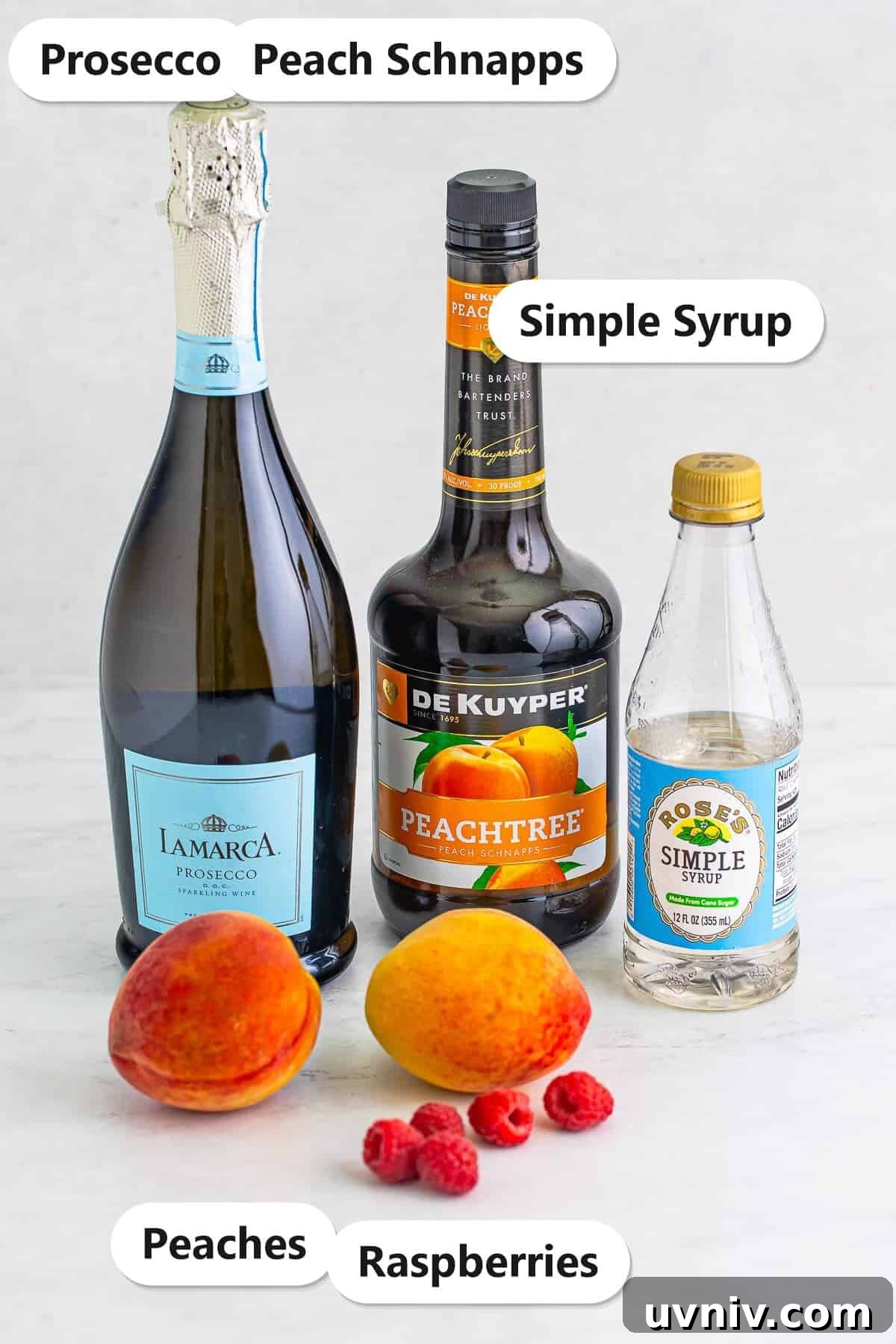 Labeled ingredients to make a peach bellini including Prosecco, peach schnapps, simple syrup, fresh peaches, and raspberries.