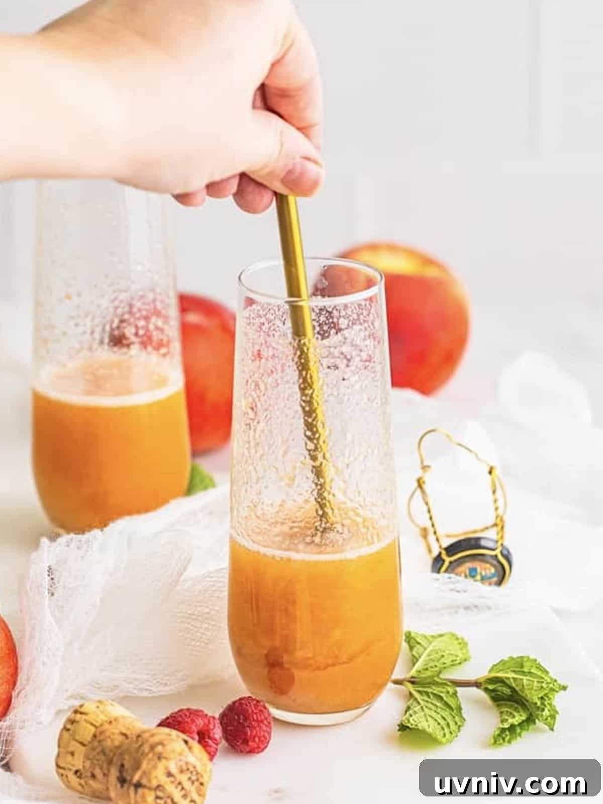 Gently stirring a peach bellini in a champagne flute.