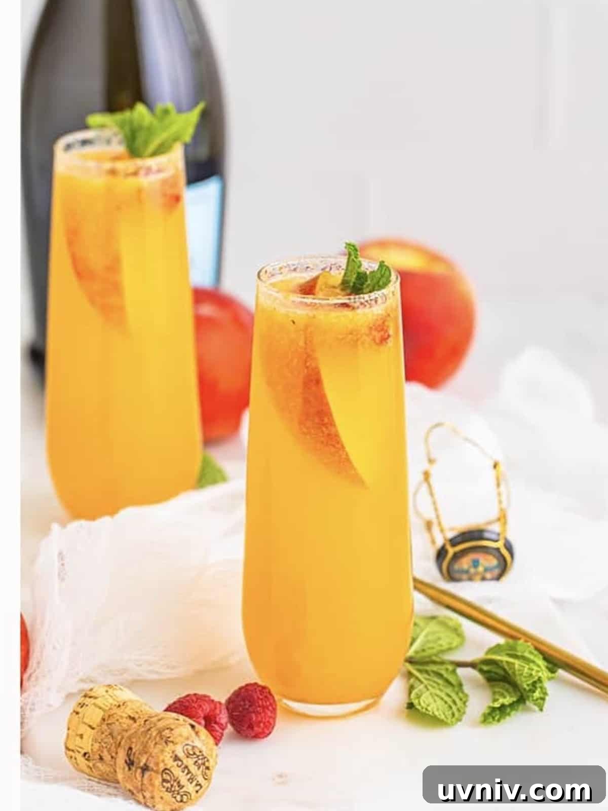 Finished peach bellini cocktails garnished with peach slices, raspberries, and mint.