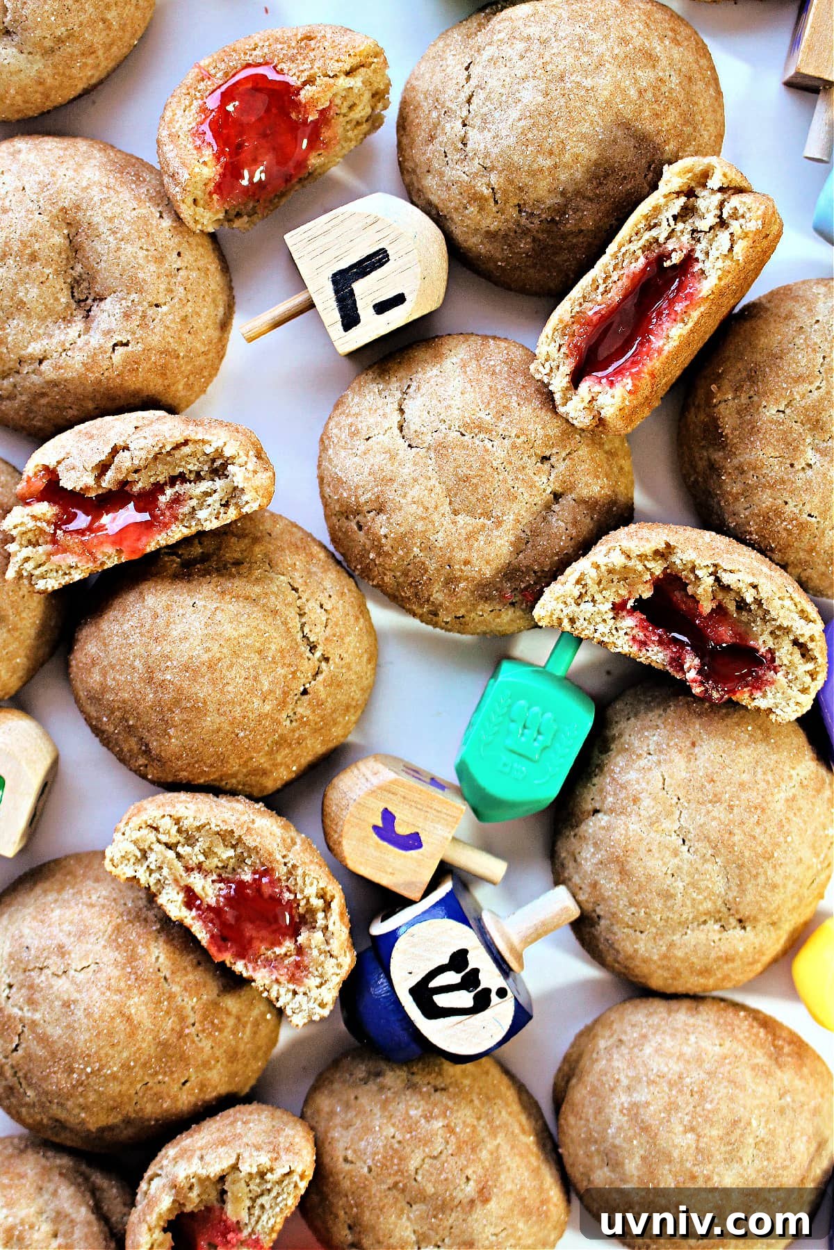 Ball shaped cookies coated in cinnamon and some open to show sugar with red jelly centers.