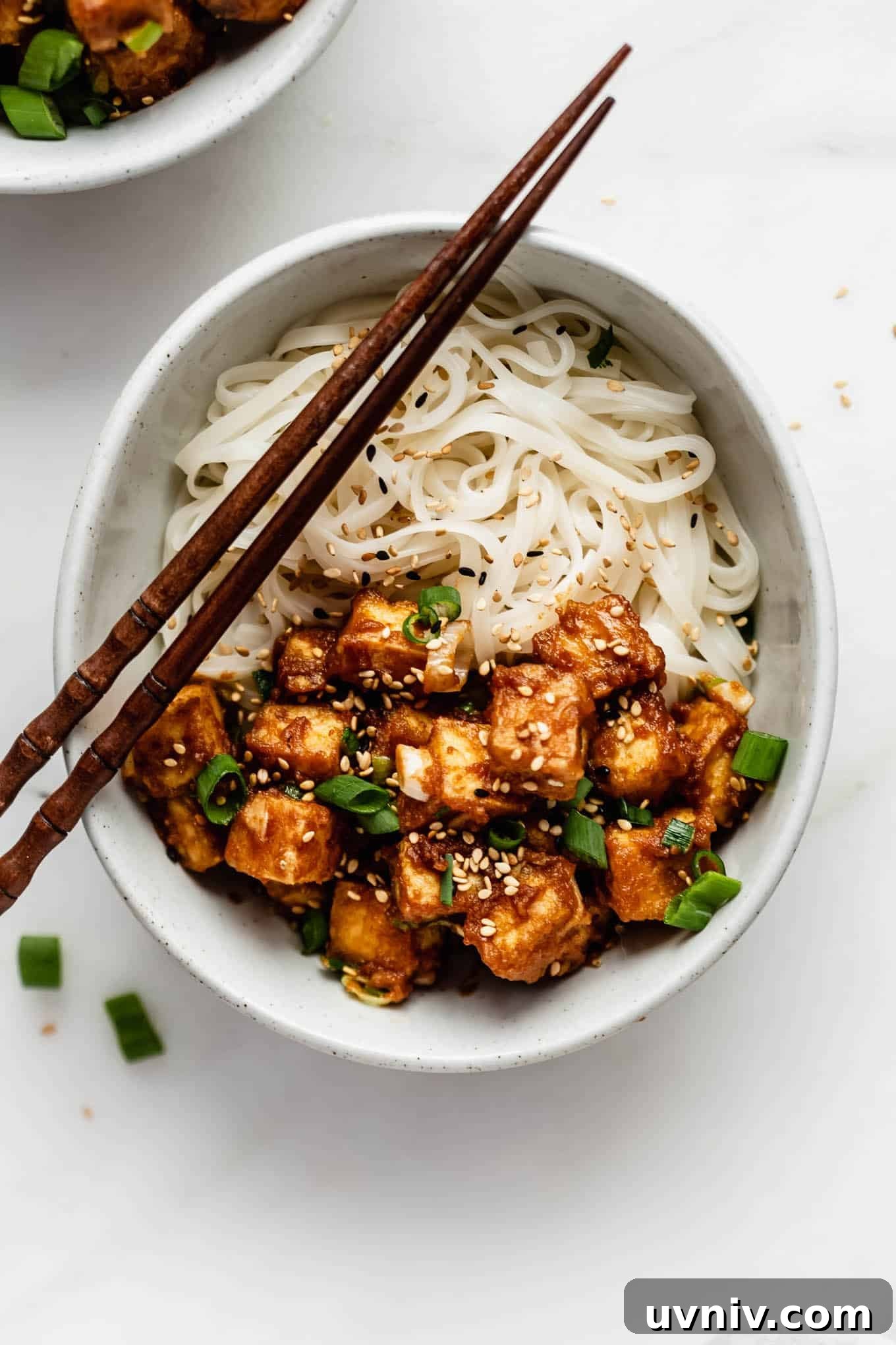 Crispy Baked Peanut Butter Tofu with Sticky Soy Glaze 2 peanut butter tofu in a bowl with rice noodles and chopsticks.