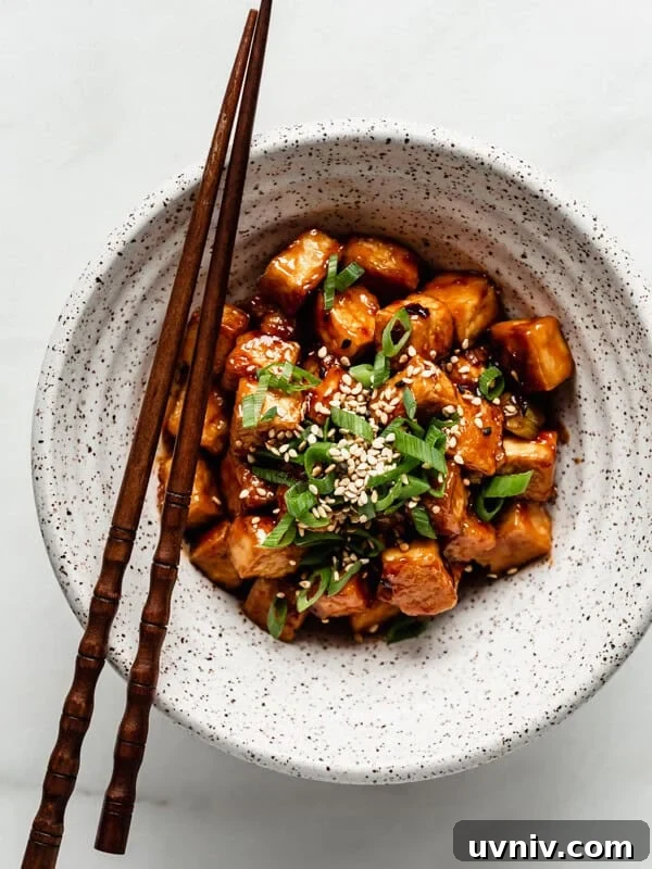 Crispy Baked Peanut Butter Tofu with Sticky Soy Glaze 12 General Tso Tofu in a speckled ceramic bowl with wooden chopsticks on the side