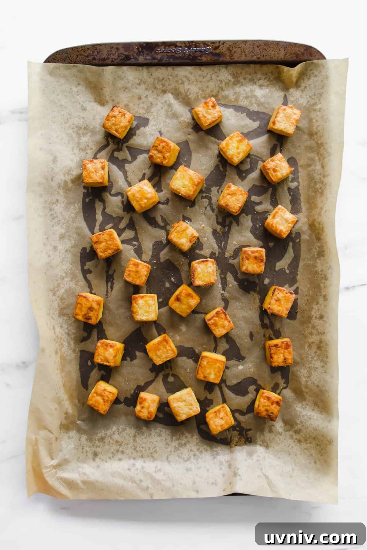 Crispy Baked Peanut Butter Tofu with Sticky Soy Glaze 5 cubes of baked tofu on a baking sheet.