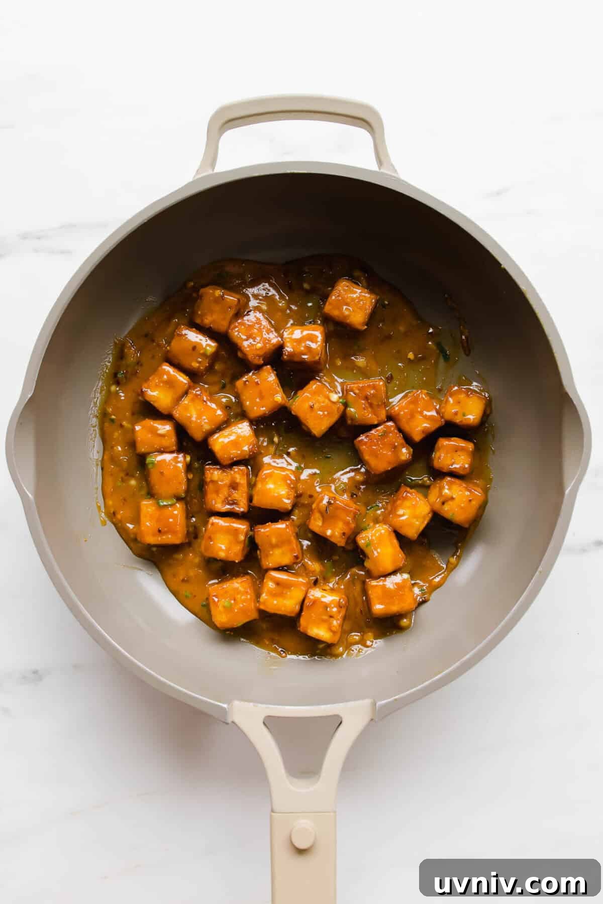 Crispy Baked Peanut Butter Tofu with Sticky Soy Glaze 8 Cubes of tofu in peanut sauce in a taupe pan.