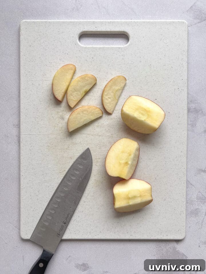 3-Ingredient Apple Nachos Recipe: Quick Sweet Snack 4 apple slices on a white cutting board with a knife placed next to them.