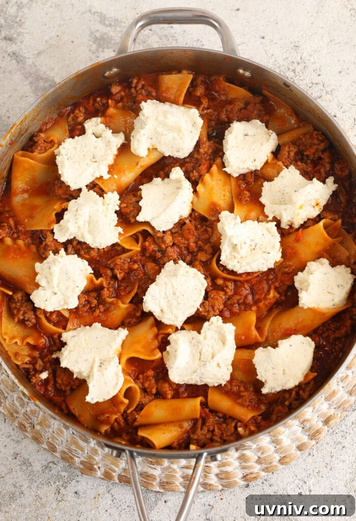 Ricotta cheese dolloped onto skillet lasagna