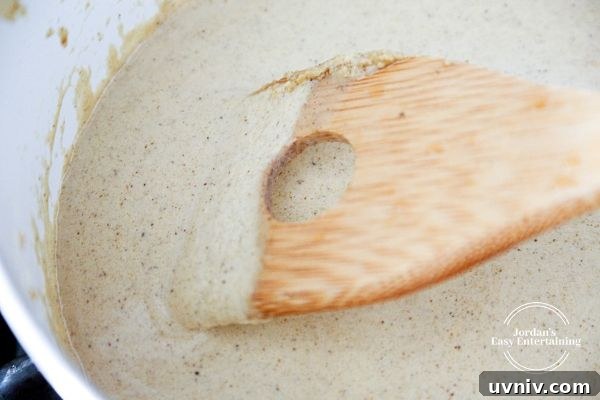 sage mustard cream sauce being stirred in a pot with a wooden spoon