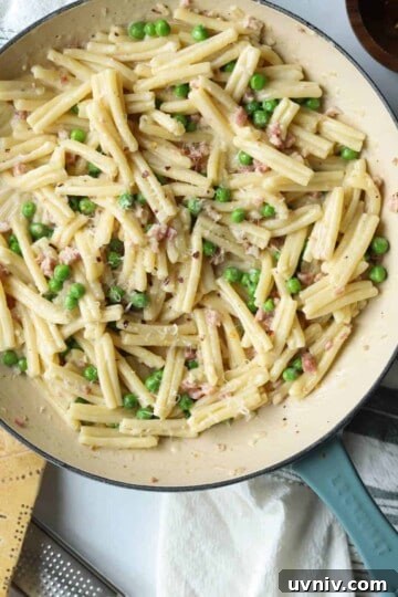 Enameled skillet with pancetta and peas topped with red pepper flakes and parmesan.