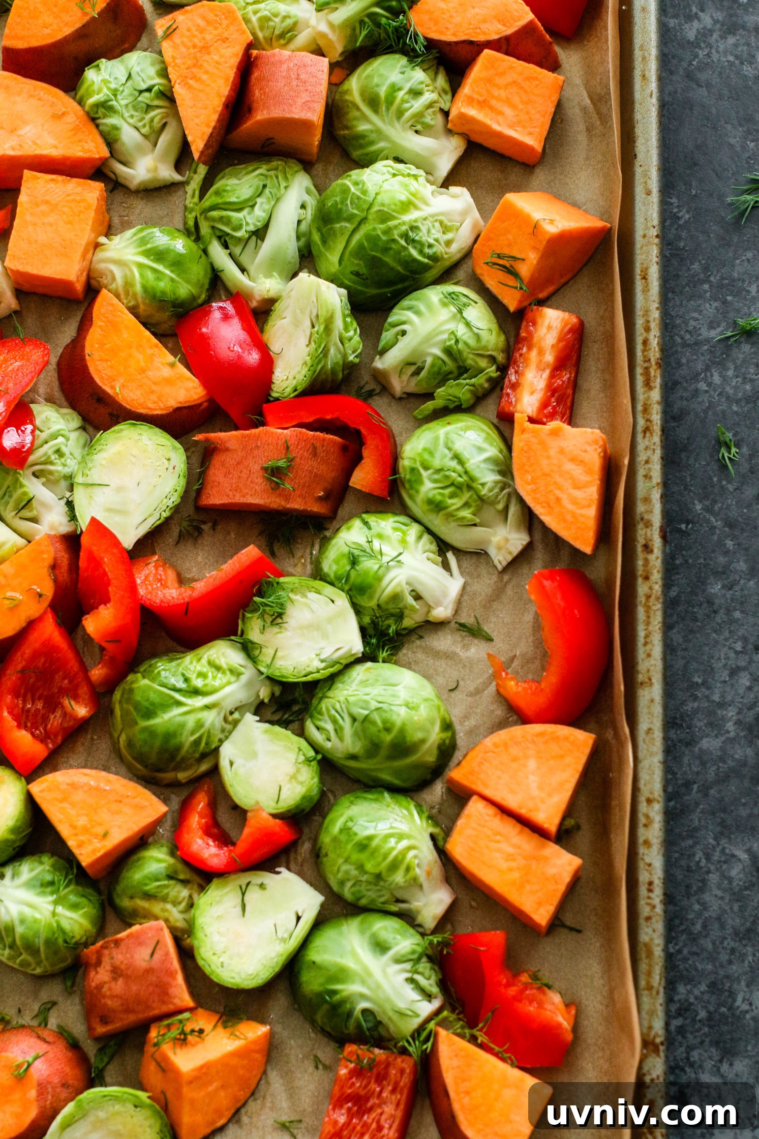sweet potato, brussels sprouts, and red pepper with dill on parchment lined baking sheet by Flora & Vino