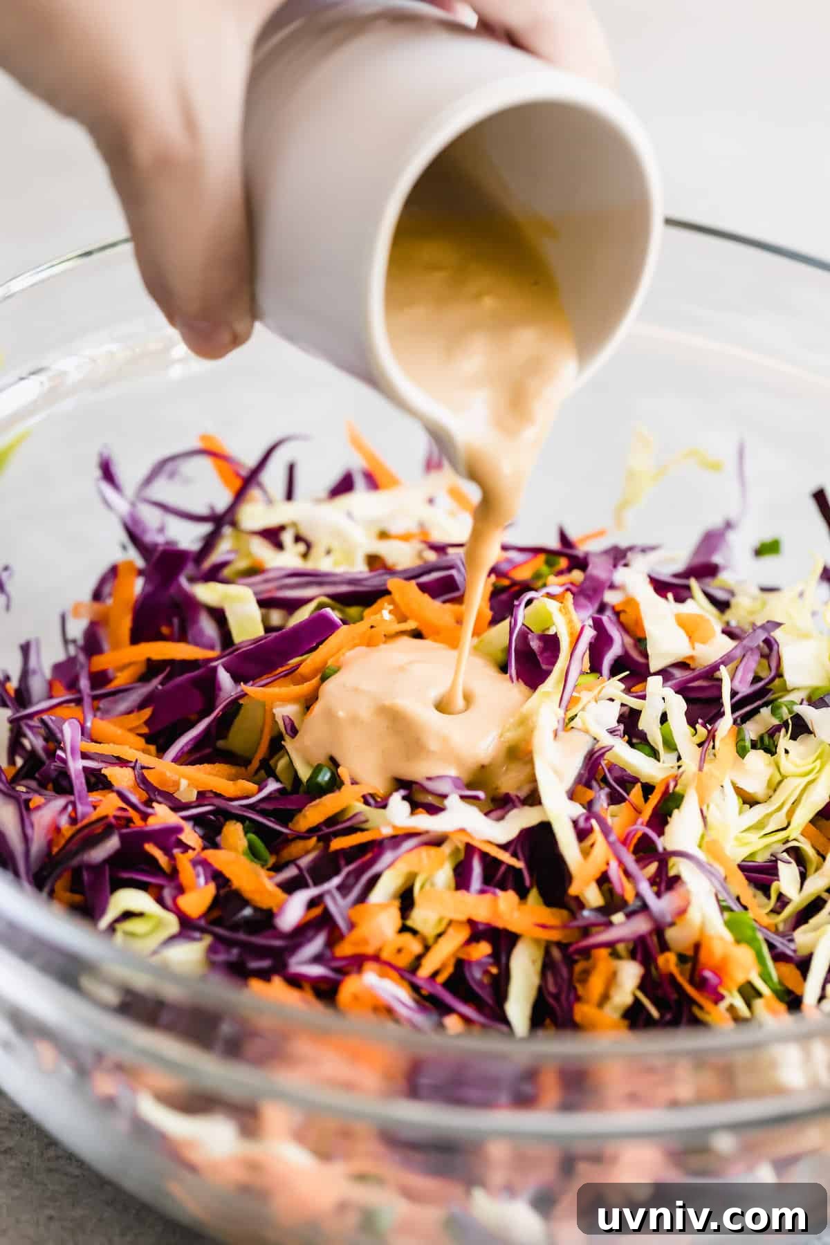 Asian Dressing Being Poured Over the Cabbage Slaw Mixture