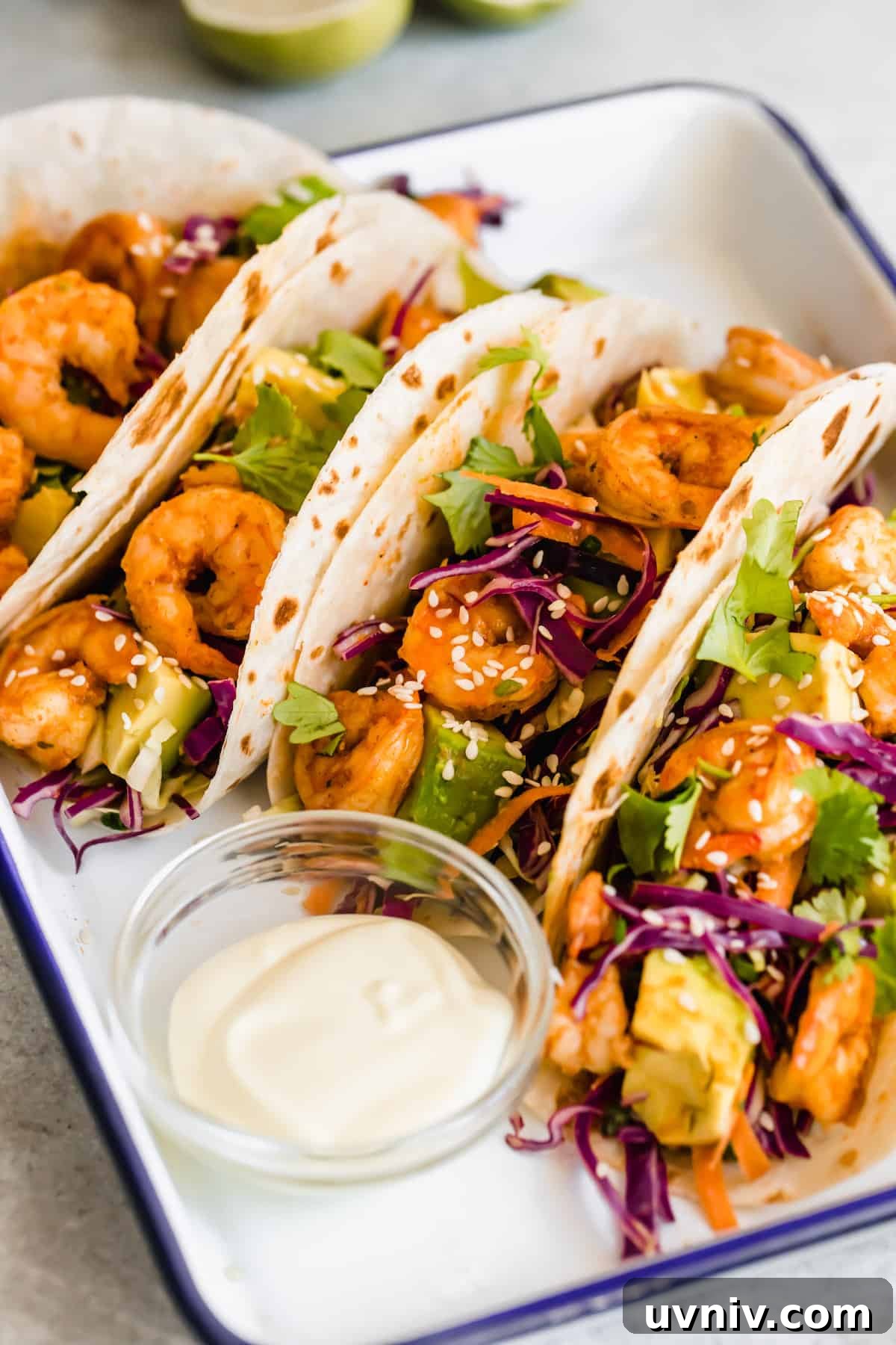 A Platter Holding Four Shrimp Tacos and a Dish of Dressing
