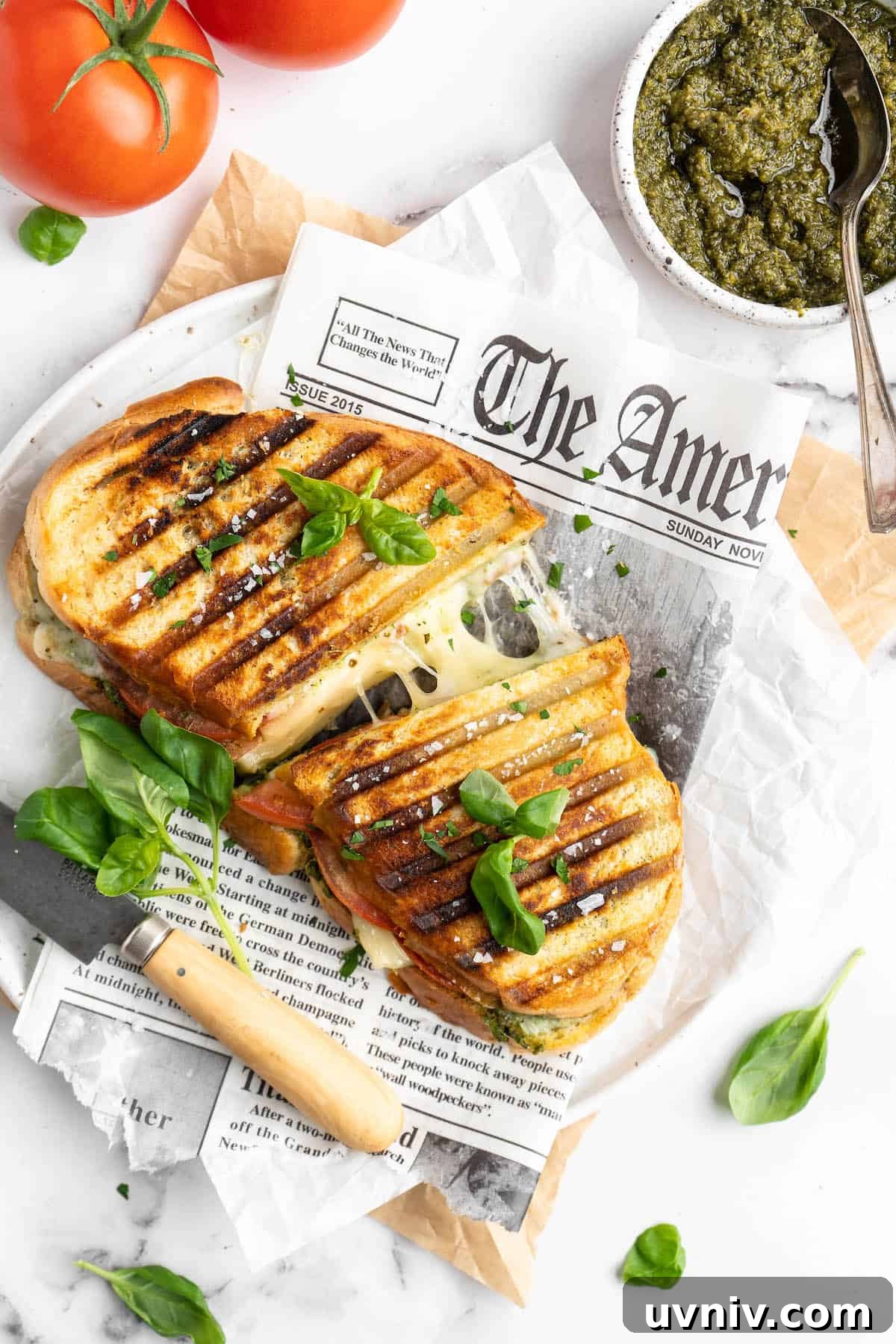 This vegan Caprese sandwich layers plant-based mozzarella with fresh tomatoes and parsley pesto, all on crusty French bread. Best lunch ever! Halved vegan caprese panini, pulled apart to show stretching cheese