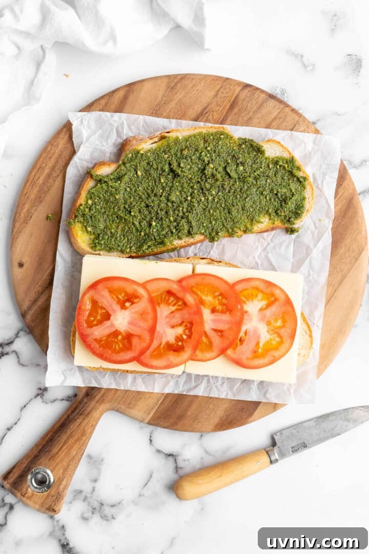 Assemble the sandwich One slice of bread spread with pesto, another topped with mozzarella and tomatoes on round cutting board