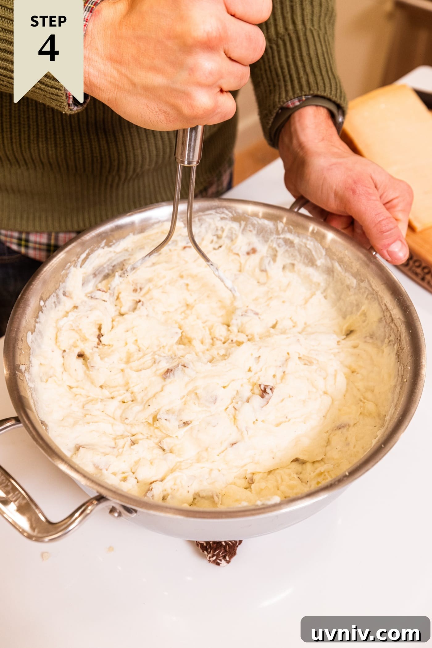 French Onion Potato Casserole Recipe with Melty Cheese 11 Hand holding potato mashed showing mashed potato mixture after adding cheese.