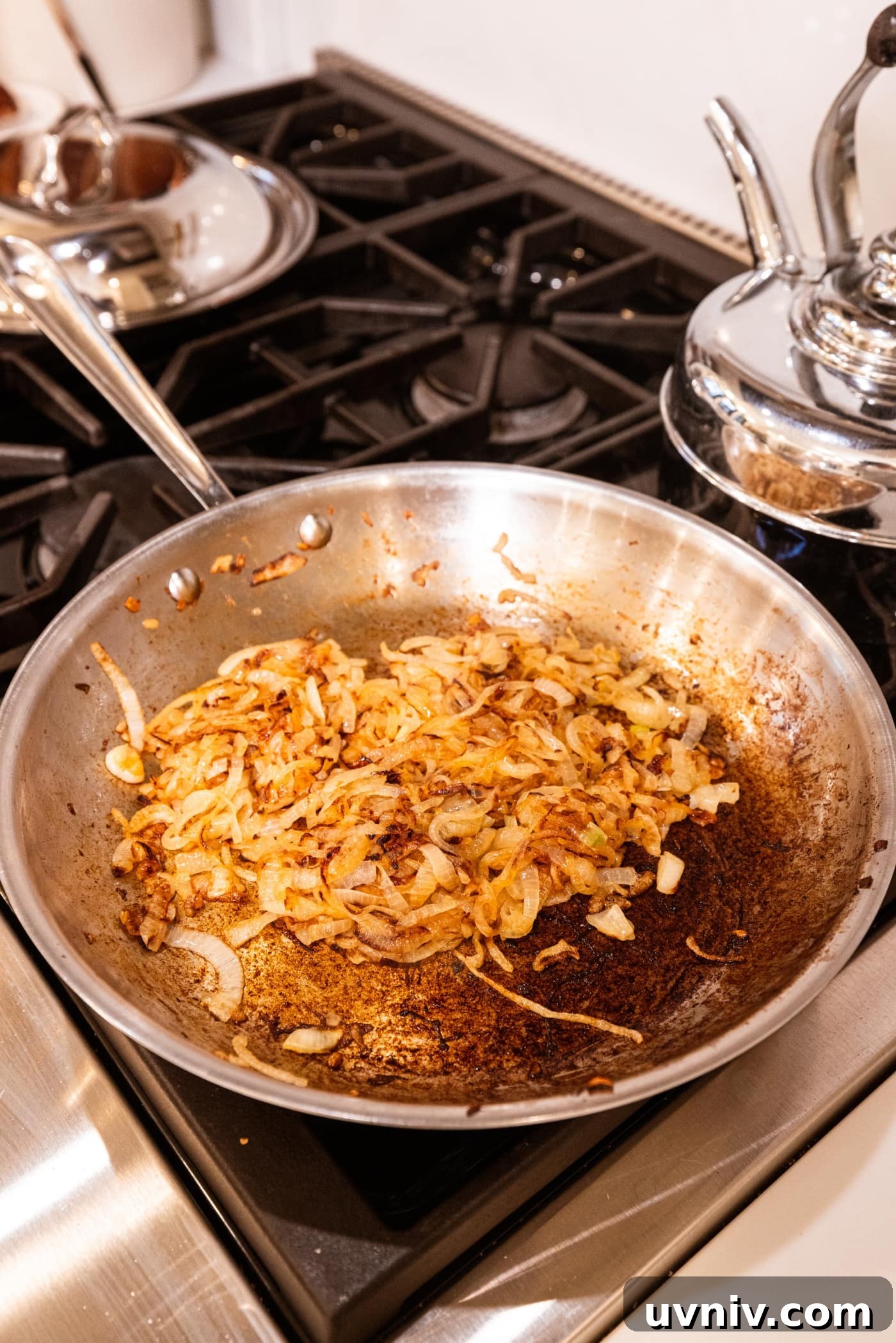 French Onion Potato Casserole Recipe with Melty Cheese 12 Caramelized onions in metal skillet on stovetop with fond on the bottom of pan.
