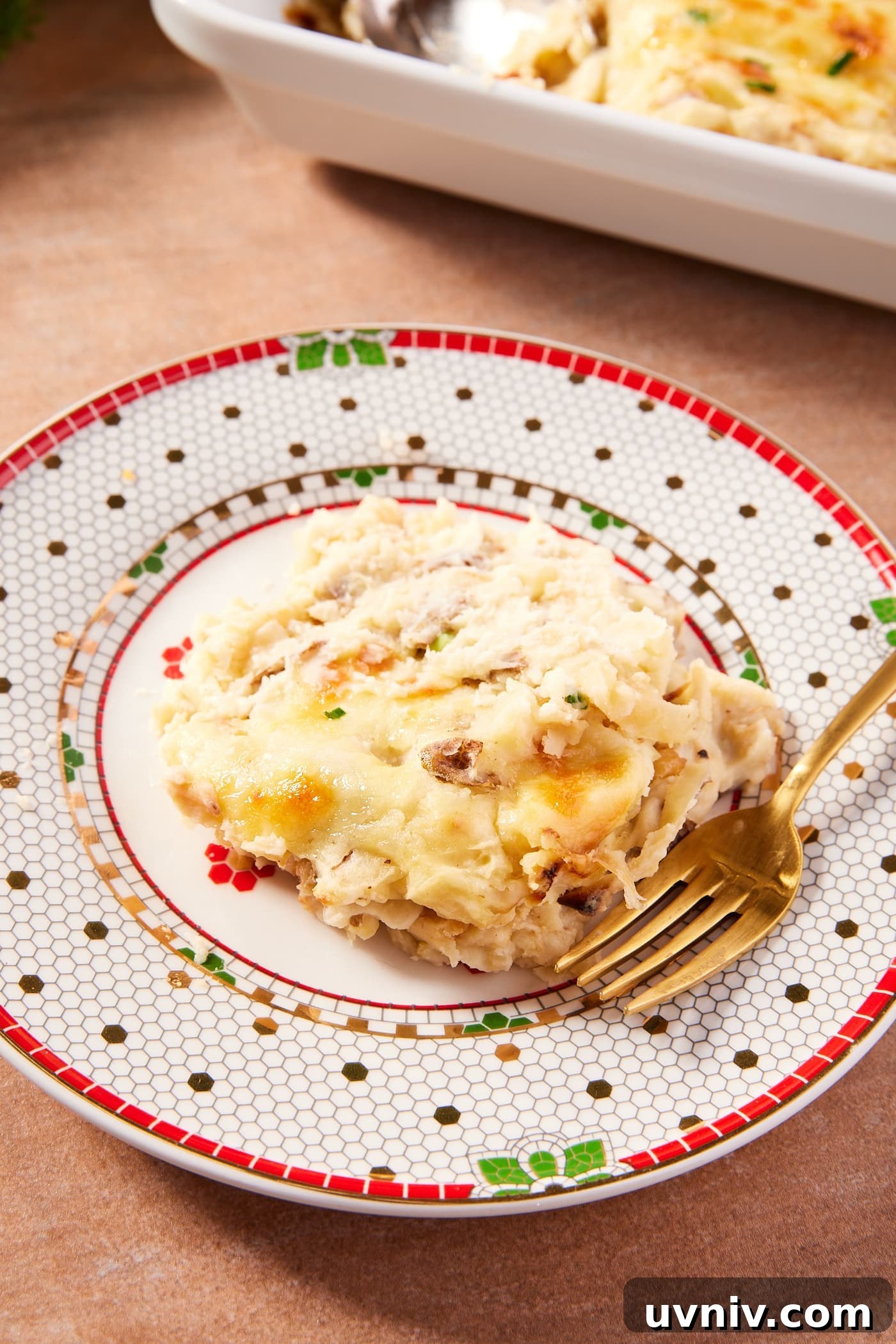 French Onion Potato Casserole Recipe with Melty Cheese 17 Holiday plate with serving of French onion potato casserole with gold fork showing cheesy texture.