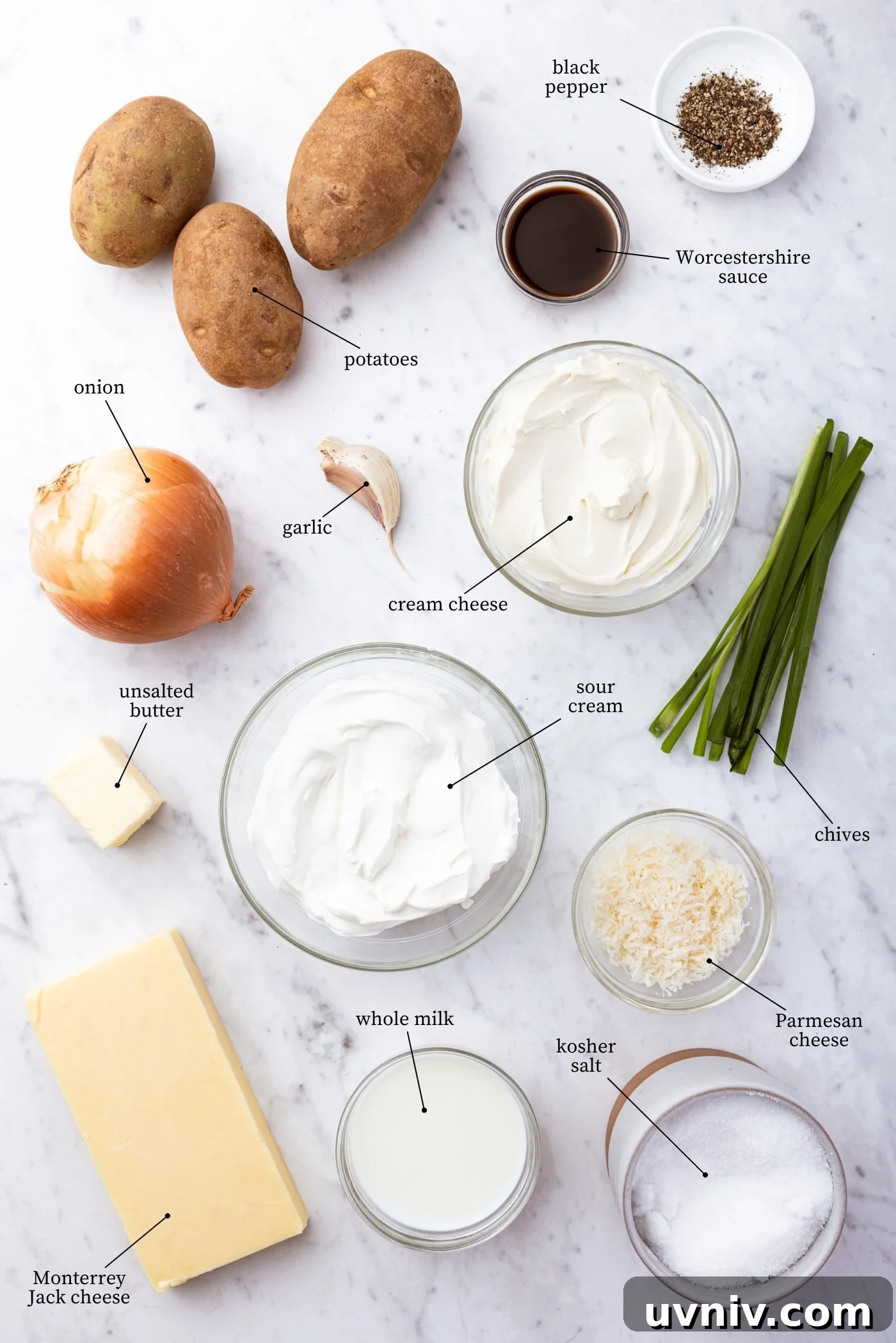 French Onion Potato Casserole Recipe with Melty Cheese 4 White marble surface filled with all ingredients needed to make French onion potato casserole including potatoes, sour cream, cream cheese, onions, cheese, and more.