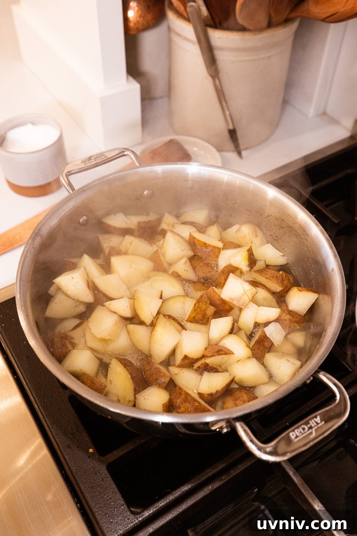 French Onion Potato Casserole Recipe with Melty Cheese 6 Metal stockpot on stove with steam rising off the top of cubed cooking potatoes.