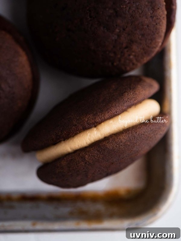 Closeup overhead image of chocolate peanut butter whoopie pies on a parchment lined baking pan.