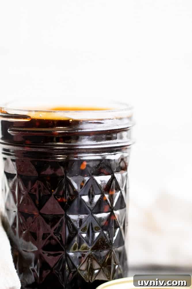Easy Homemade Teriyaki Sauce Straight on shot of teriyaki sauce in a glass mason jar with white background.