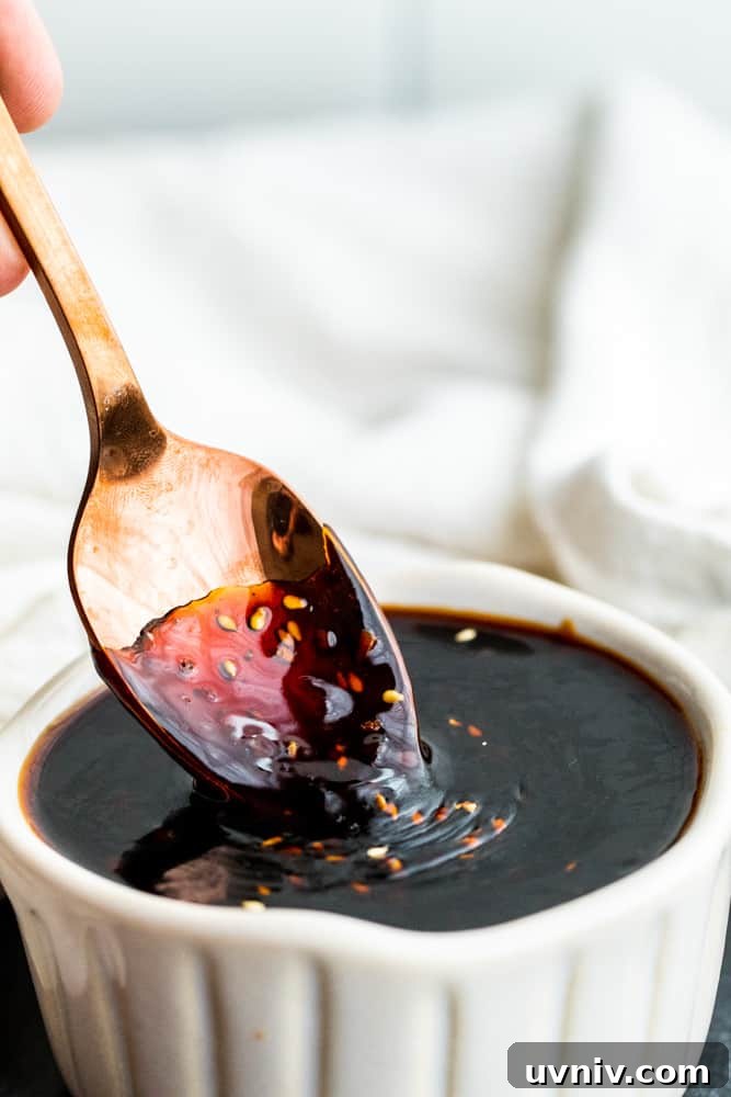 Teriyaki sauce spoon Gold spoon dipping into white bowl of teriyaki sauce.