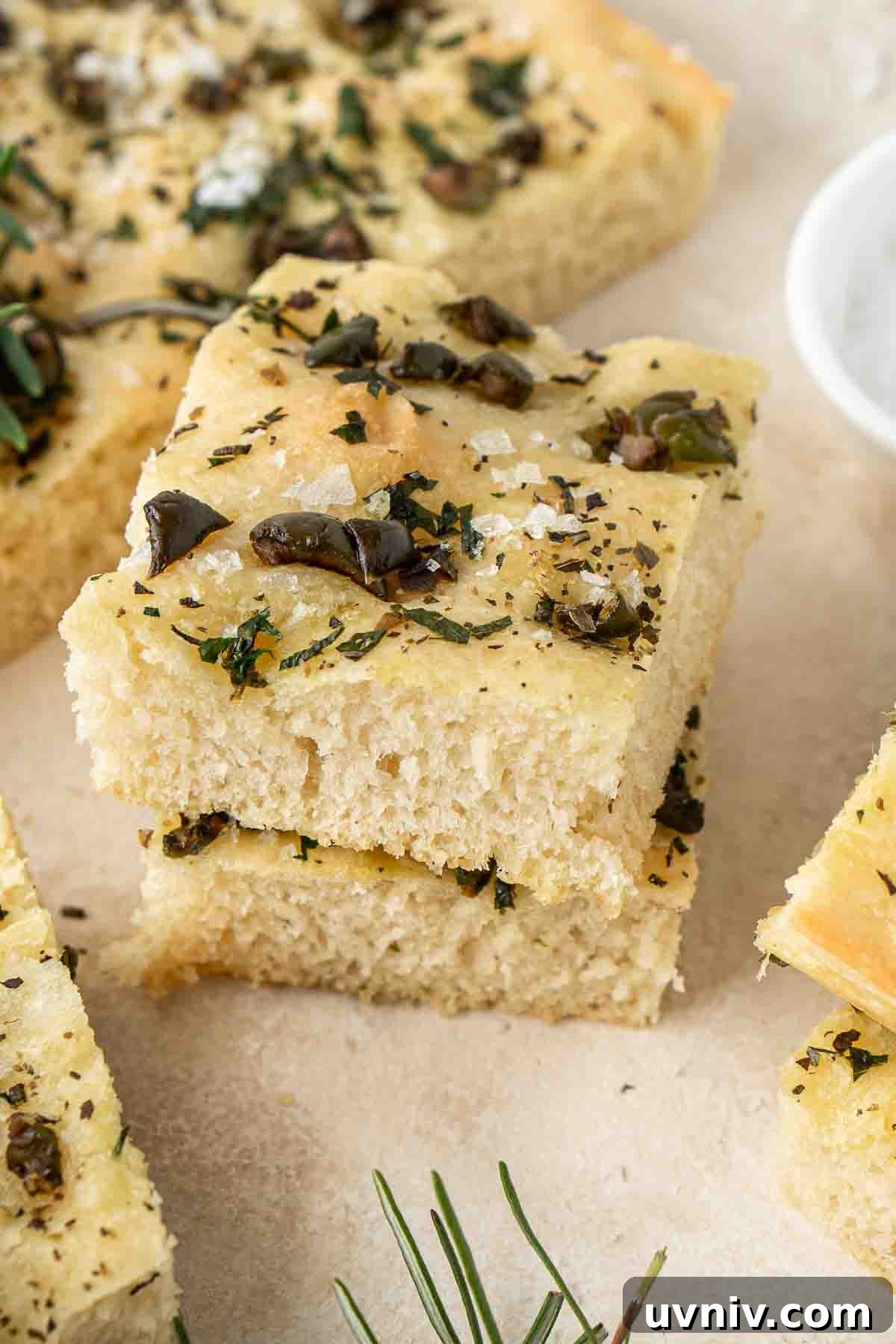 Olive & Herb Focaccia Recipe — Crispy, Flavorful Italian Bread 12 Two sliced of focaccia stacked on top of each other.