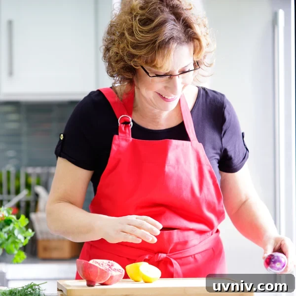 Roasted Tomato Sauce Recipe — Rich Flavor in Minutes 12 Beth Lee in red apron looking at vegetables on cutting board