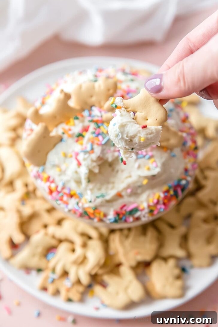 Funfetti Cake Dip Recipe — Party-Friendly Dessert Dip 6 hand dipping animal cracker in funfetti dip