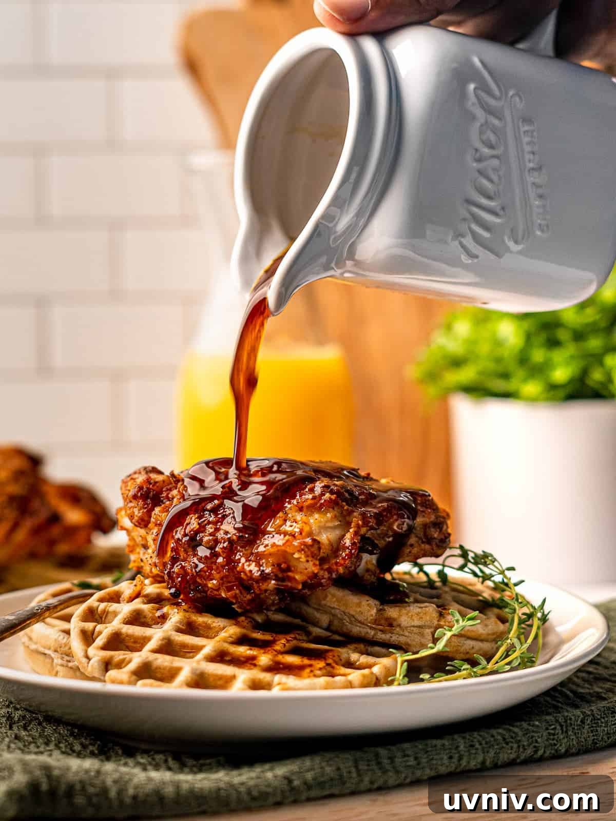 Syrup being poured onto chicken and waffles.