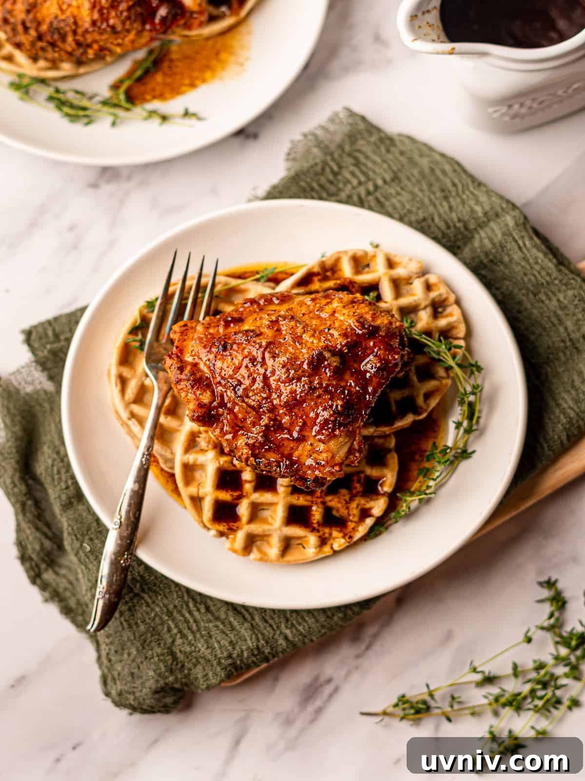 A plate of chicken and waffles on a green linen.