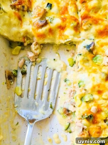 A tray of creamy lasagna with a spatula