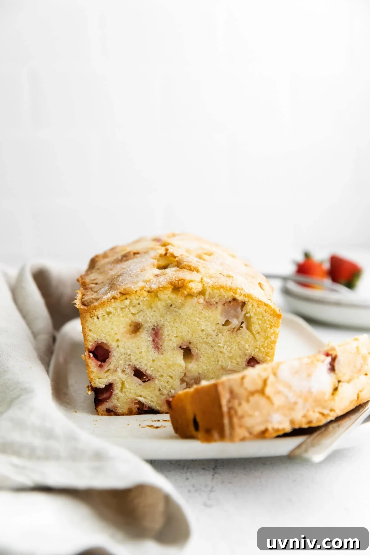 Strawberry Rhubarb Layer Cake Recipe for Summer Baking 2 cross-section of strawberry rhubarb cake on a cake plate.