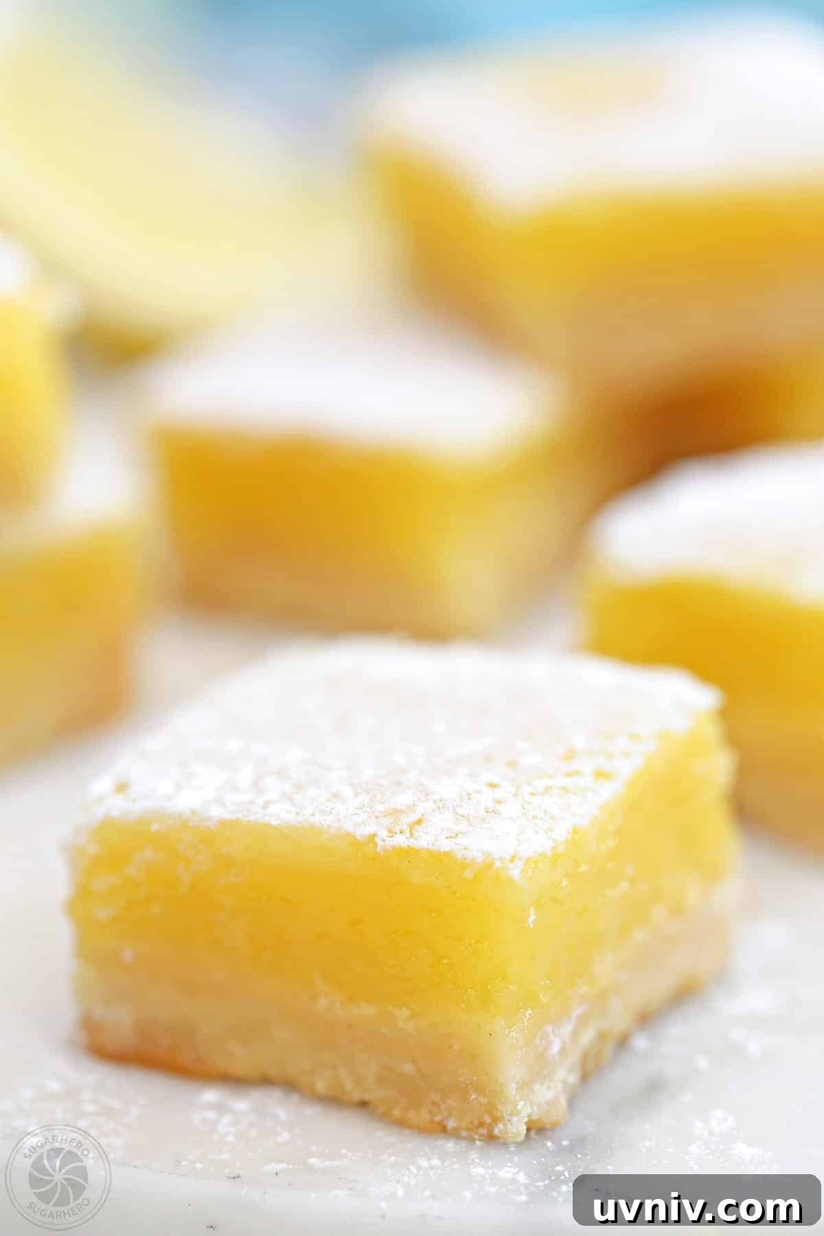 Zesty Lemon Bars: Classic Tangy Dessert Bar Recipe 16 Close up of a lemon bar with more bars in the background.