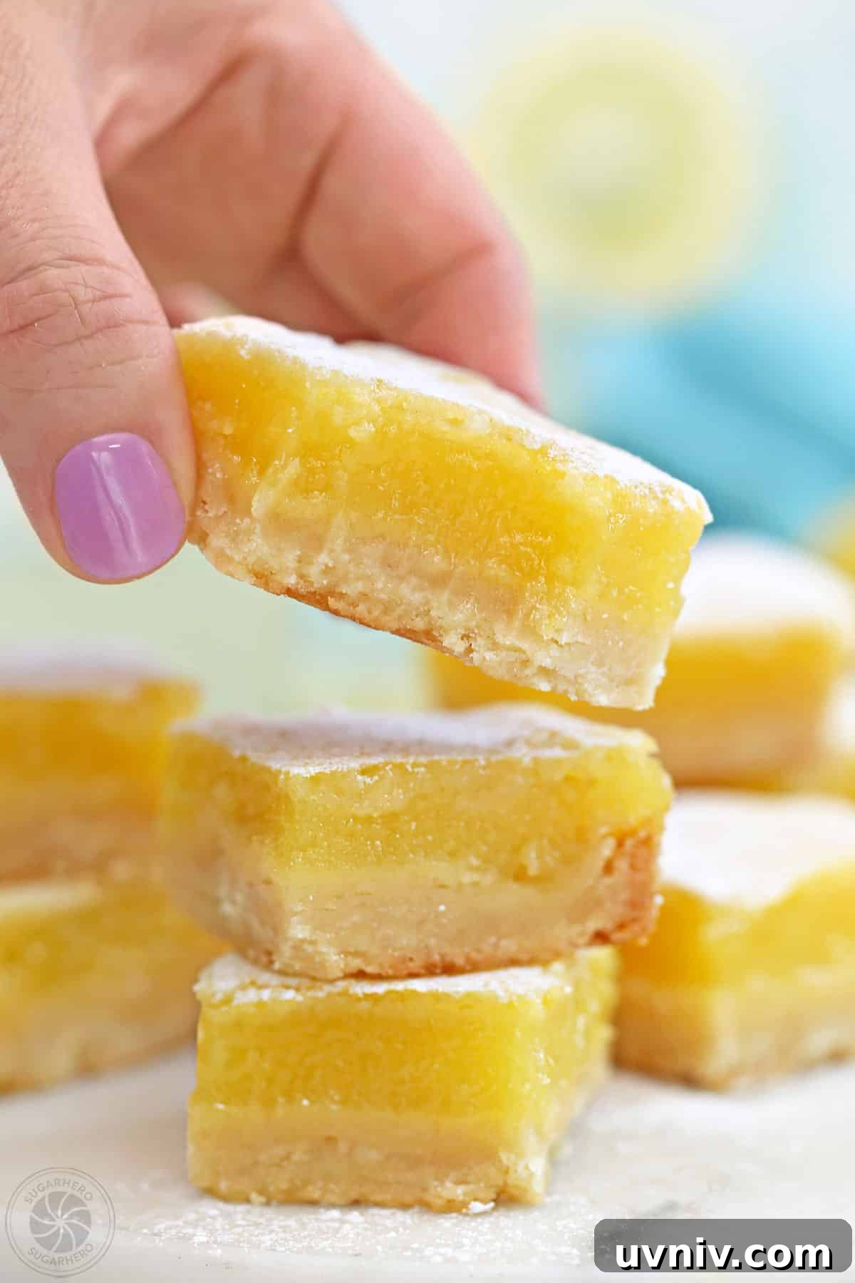 Zesty Lemon Bars: Classic Tangy Dessert Bar Recipe 4 Hand picking up a lemon bar from a stack.