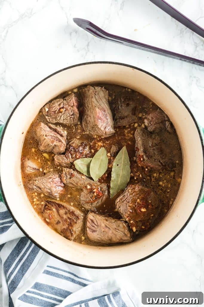 Chipotle Beef Barbacoa Recipe: Smoky Slow-Cooked Mexican Beef 8 beef chunks cooking in chipotle sauce
