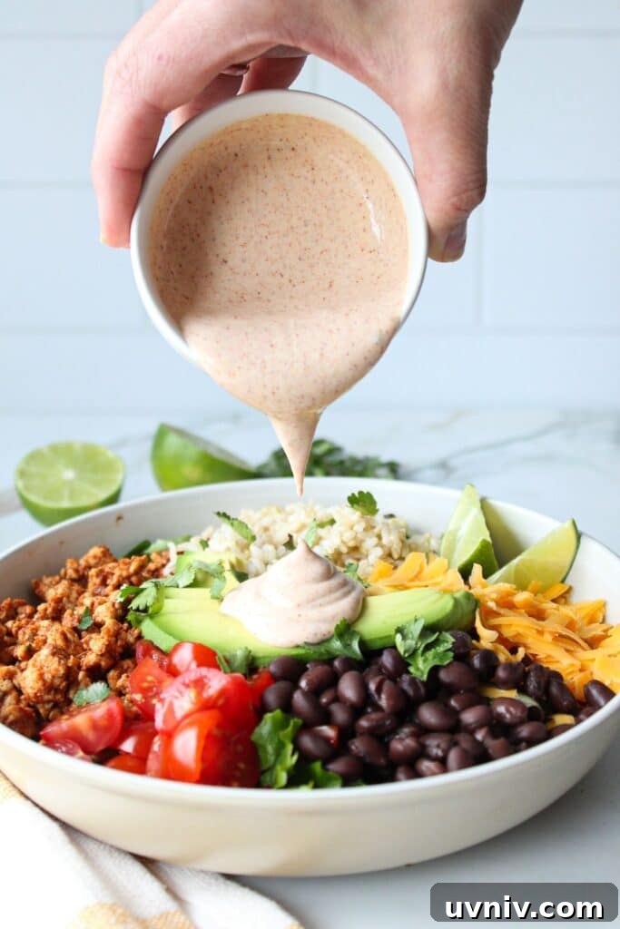 Taco Rice Bowl with Seasoned Beef, Salsa & Avocado 5 Creamy taco dressing being poured onto a taco rice bowl.