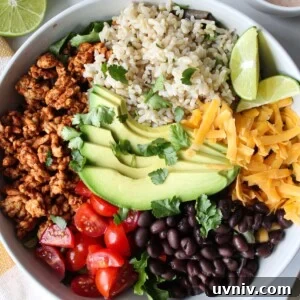 A taco rice bowl with ground turkey, rice, avocado, tomato, black beans, and shredded cheese with a creamy taco dressing on the side.