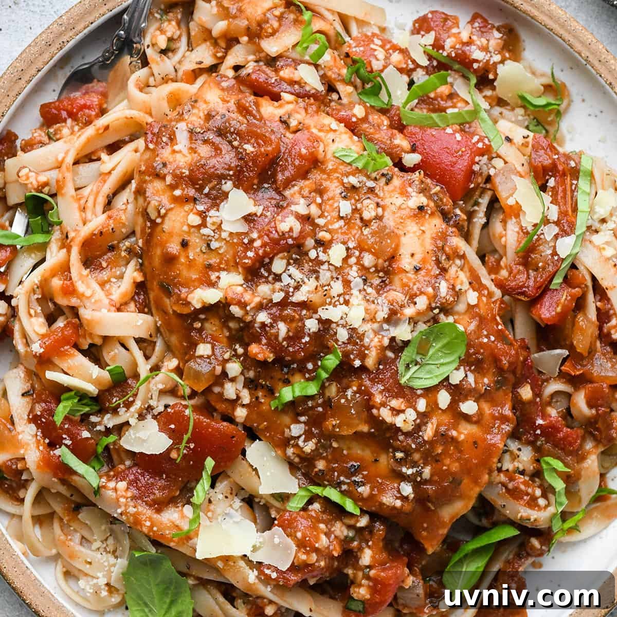 Slow Cooker Italian Chicken Recipe for Tender, Flavorful Meals 11 Slow Cooker Italian Chicken breast on top of pasta on a plate garnished with basil and parmesan cheese