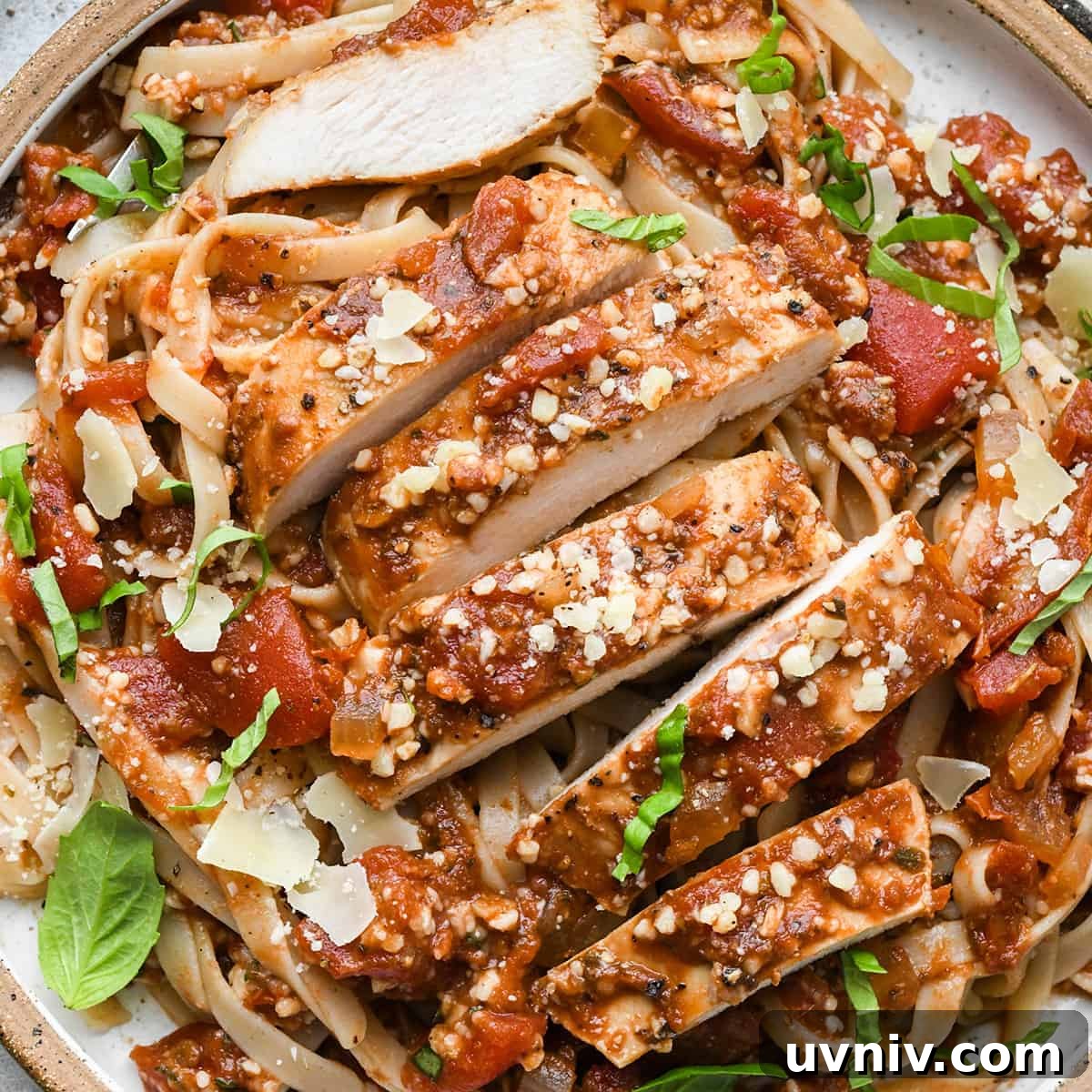 Slow Cooker Italian Chicken Recipe for Tender, Flavorful Meals 12 Slow Cooker Italian Chicken breast cut into strips on top of pasta on a plate garnished with basil and parmesan cheese