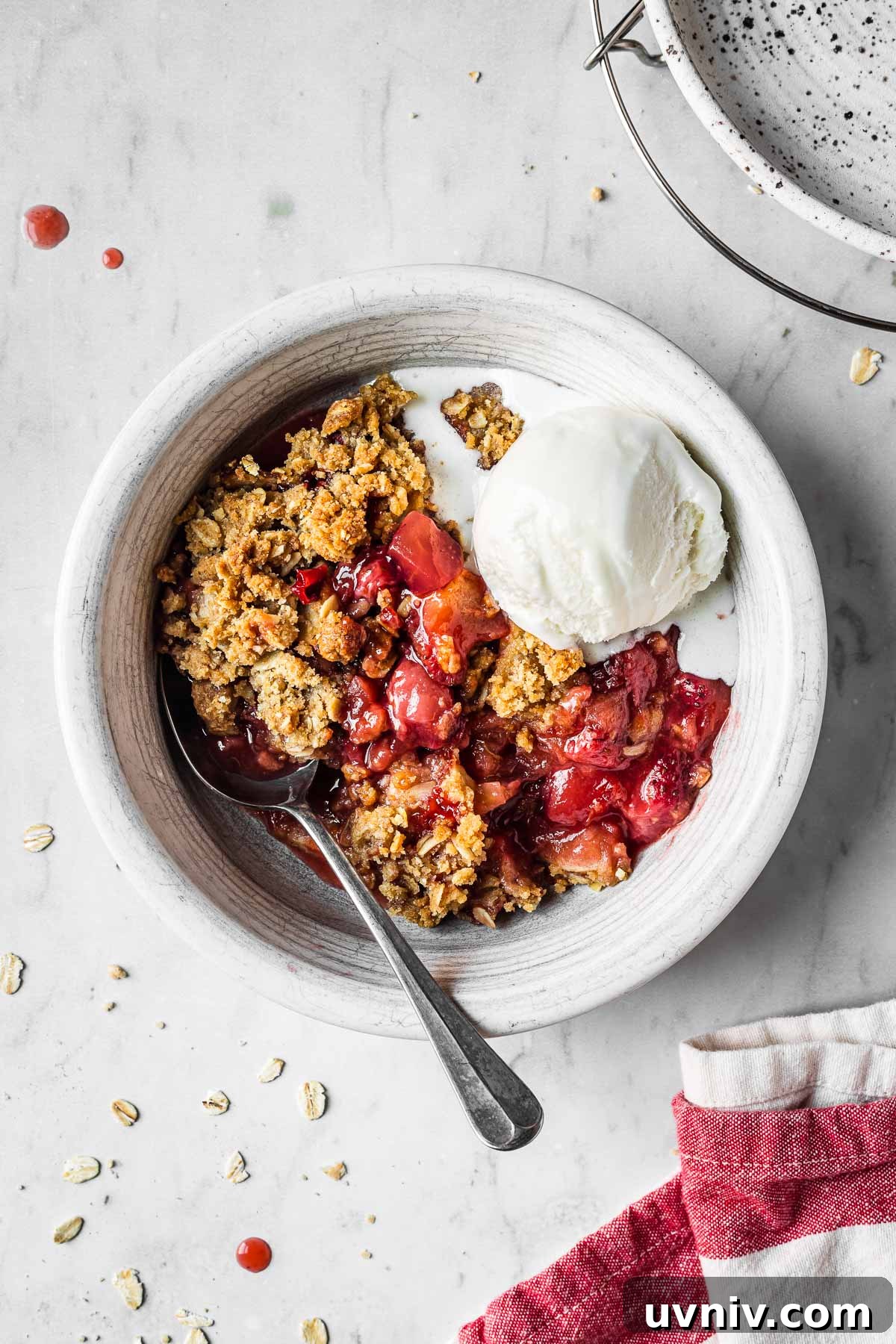 A bowl filled with strawberry apple crisp and a scoop of vanilla ice cream.