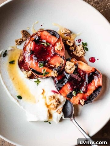 Grilled peaches with creamy cheese and honey in a low bowl with a spoon.