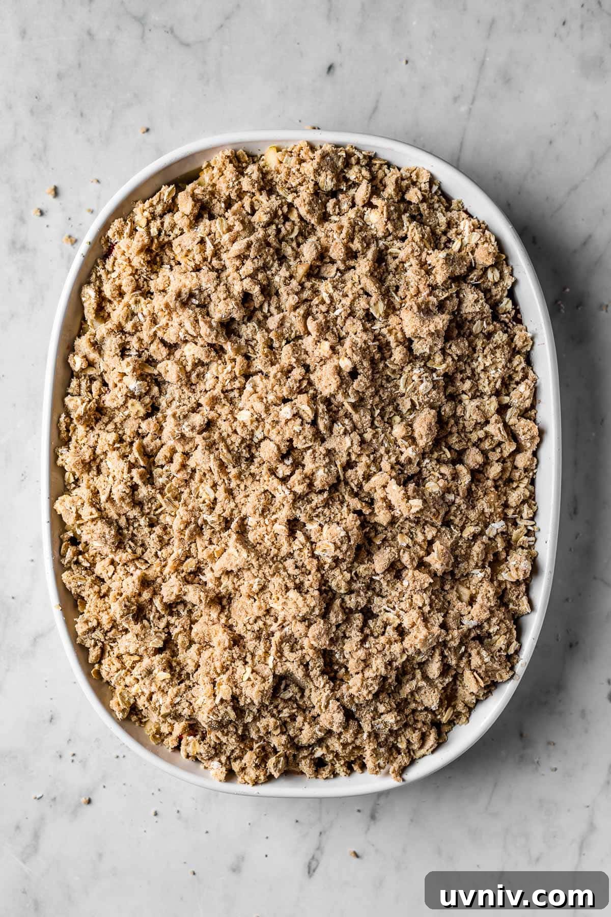 A dish of unbaked fruit crisp covered with topping.