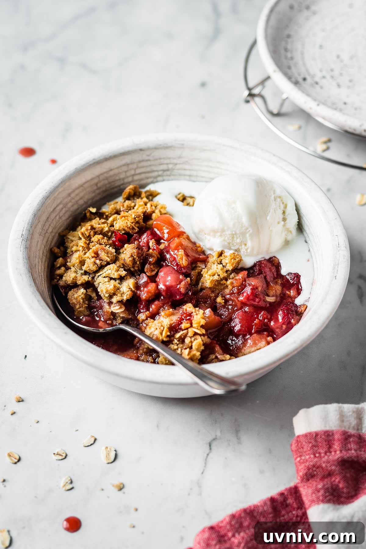 A bowl of fruit crisp topped with vanilla ice cream.