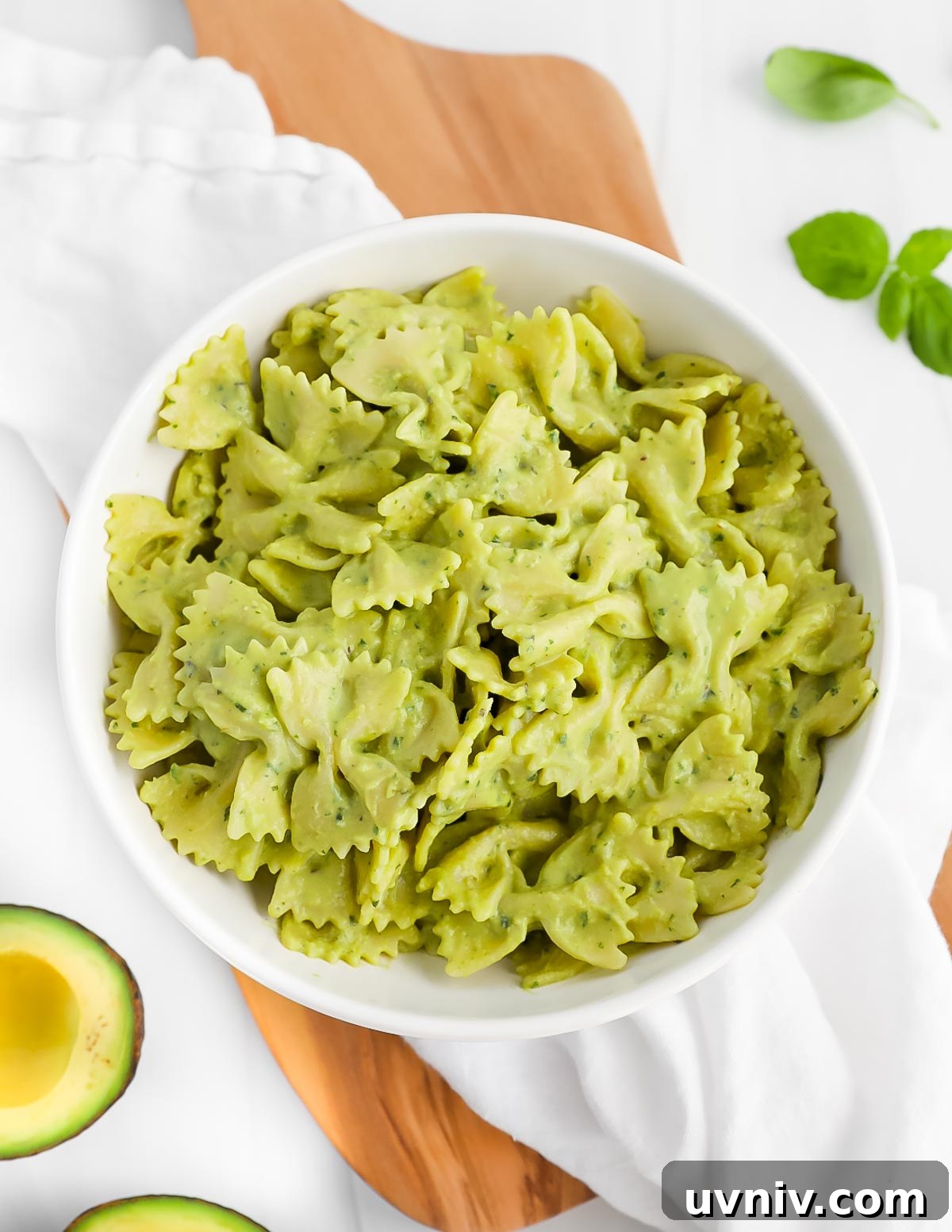 Creamy Lemon Herb Tahini Sauce Recipe for Salad & Dips 4 Bowtie pasta covered in a green sauce in a white bowl.