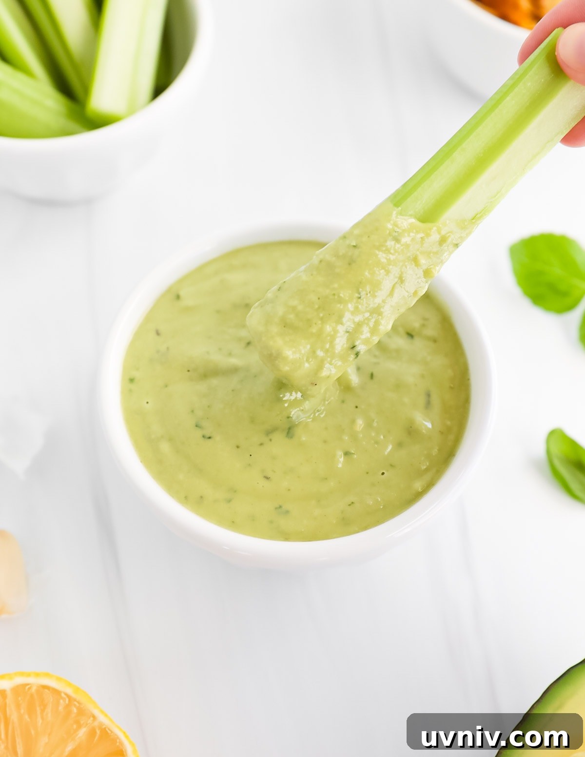 Creamy Lemon Herb Tahini Sauce Recipe for Salad & Dips 6 A piece of celery covered in a green creamy sauce.