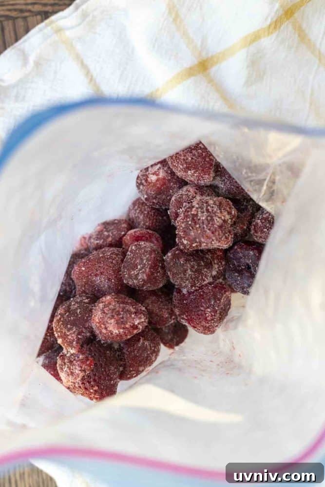 Freeze Strawberries Properly: Step-by-Step Guide for Fresh Flavor 3 an open bag of frozen strawberries on a white and yellow checked towel