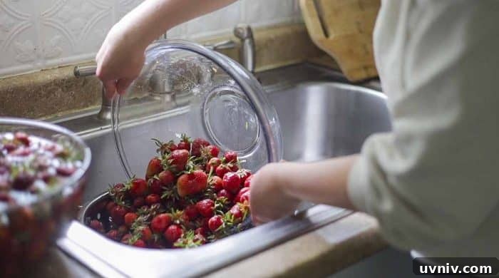 Freeze Strawberries Properly: Step-by-Step Guide for Fresh Flavor 6 pouring strawberries into a strainer in a sink