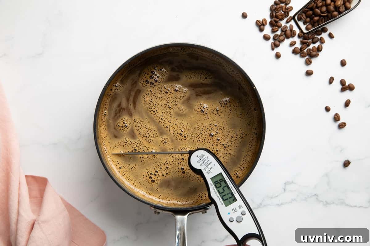 Homemade Espresso Ice Cream Recipe — Rich Coffee Gelato 5 A saucepan with combined egg yolks, sugar and milk with espresso powder in it. A thermometer is in it to read the temperature.